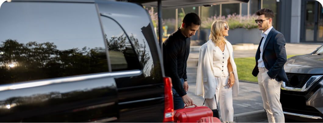 an assistant placing a couples suitcase in the car