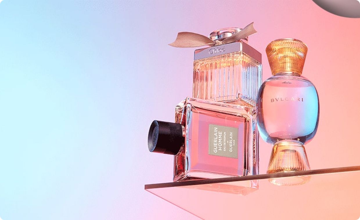 Three perfume bottles against blue and pink gradient background