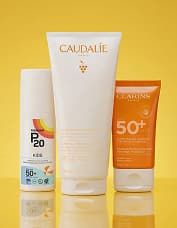 Three sunscreen products on a yellow background, featuring SPF ratings of 50+.