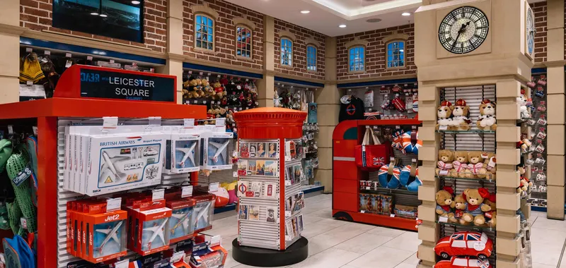 Toy store with London-themed décor, featuring red accents, teddy bears, toy planes, buses, and a clock tower display.