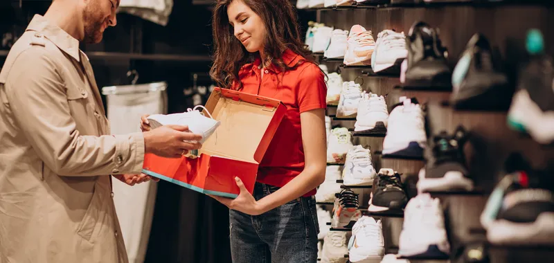 Shop staff member showing shoe in box to customer