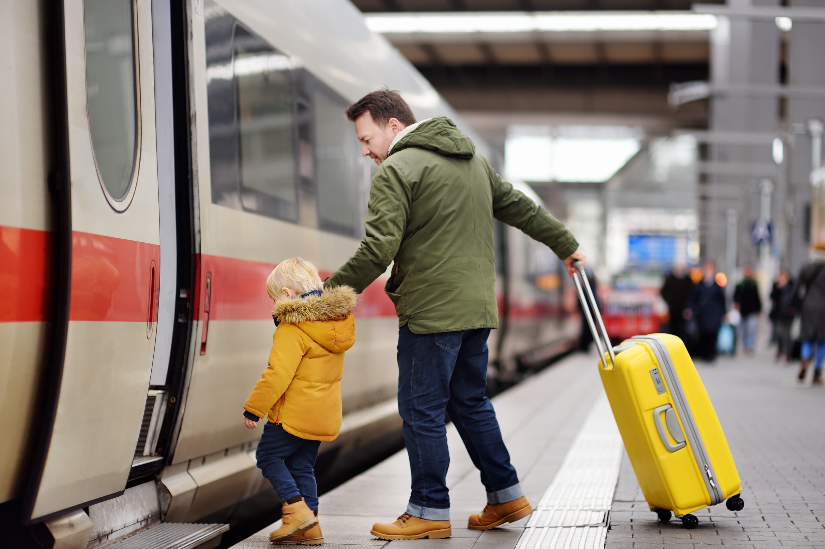 Man and little boy getting on train
