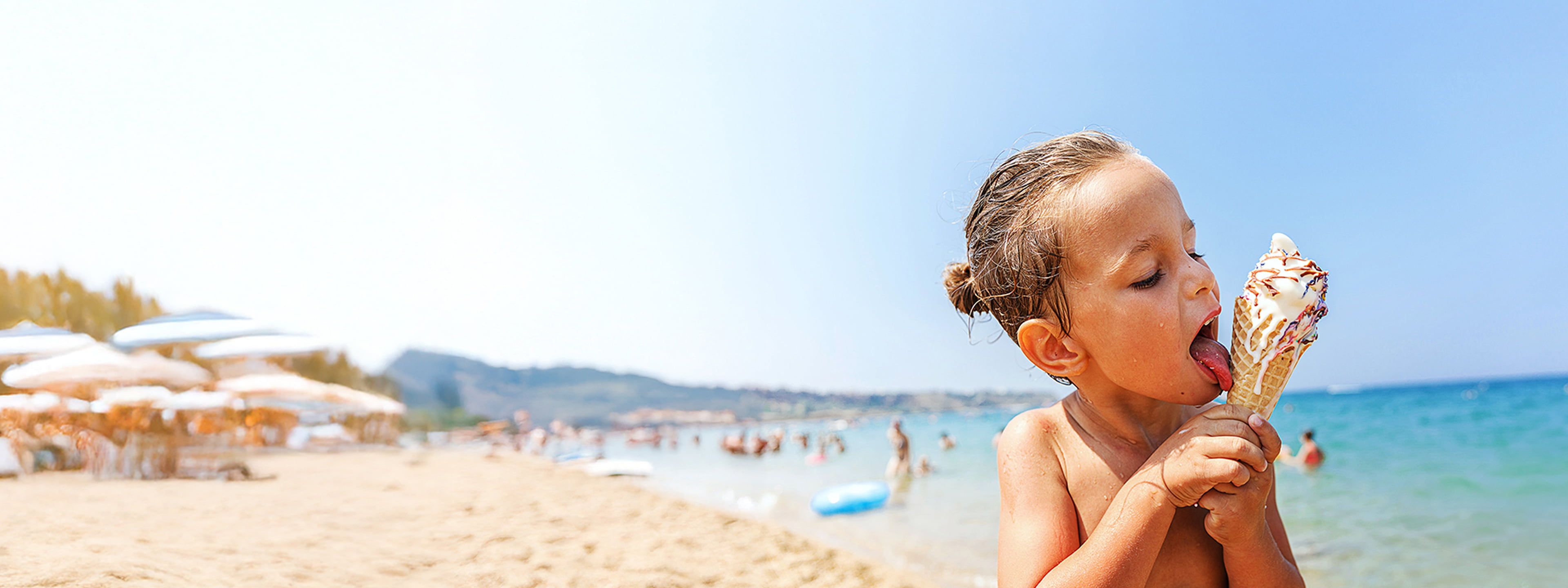 Little girl licking ice cream on beach