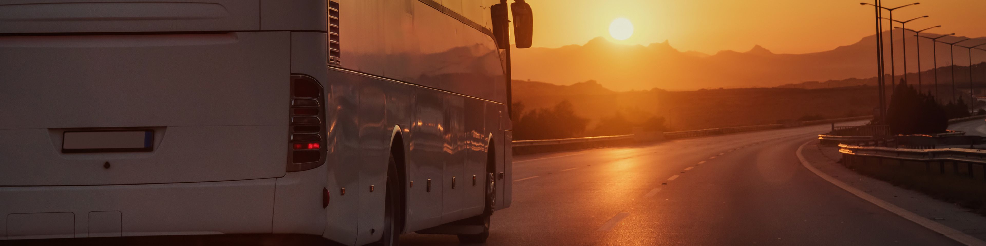 Bus driving down road into sunset
