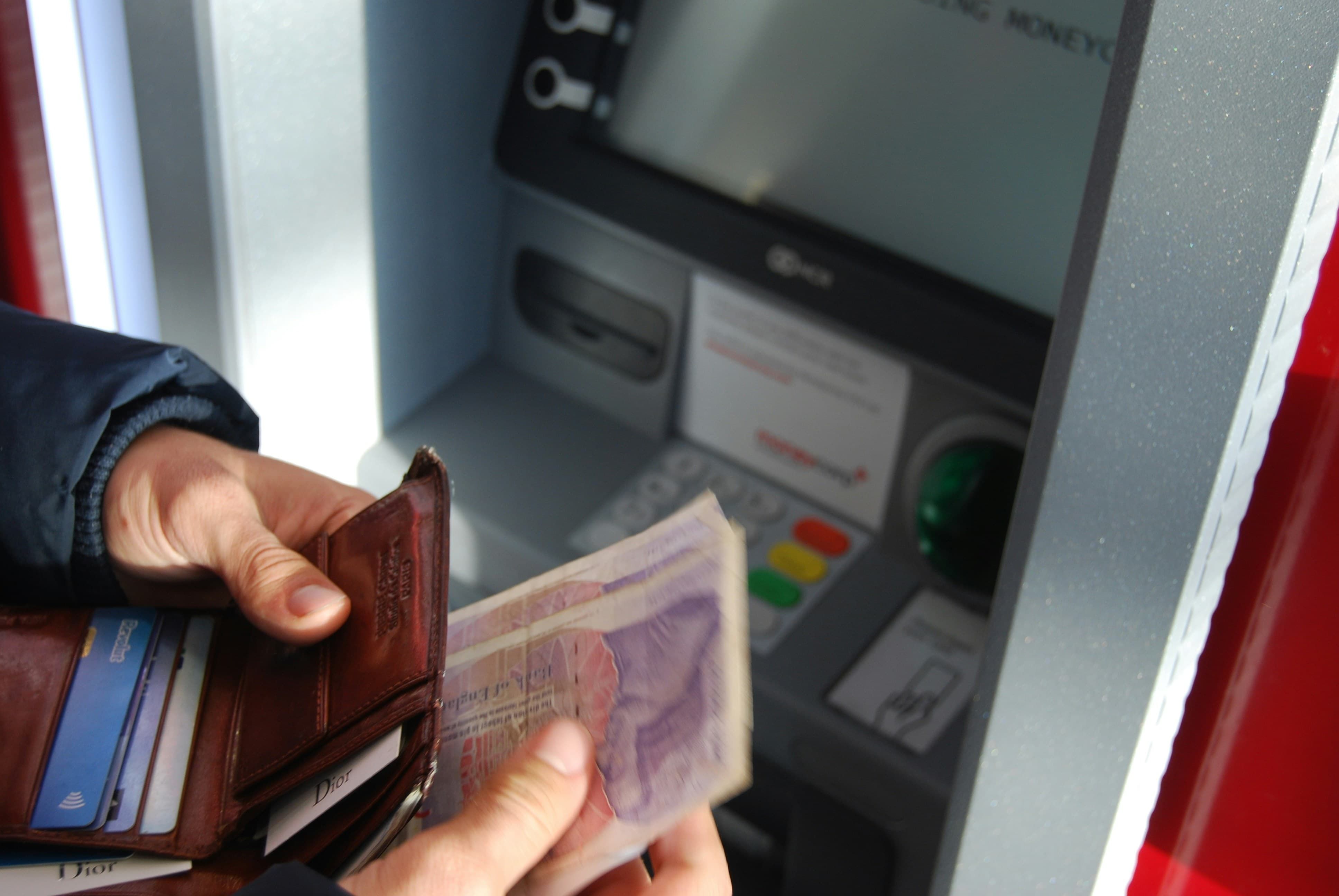 Someone putting cash in wallet after getting it out of machine