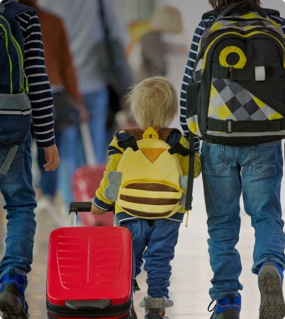 Little boy holding hand whilst pulling suitcase