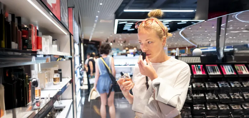 Woman smelling perfume in shop