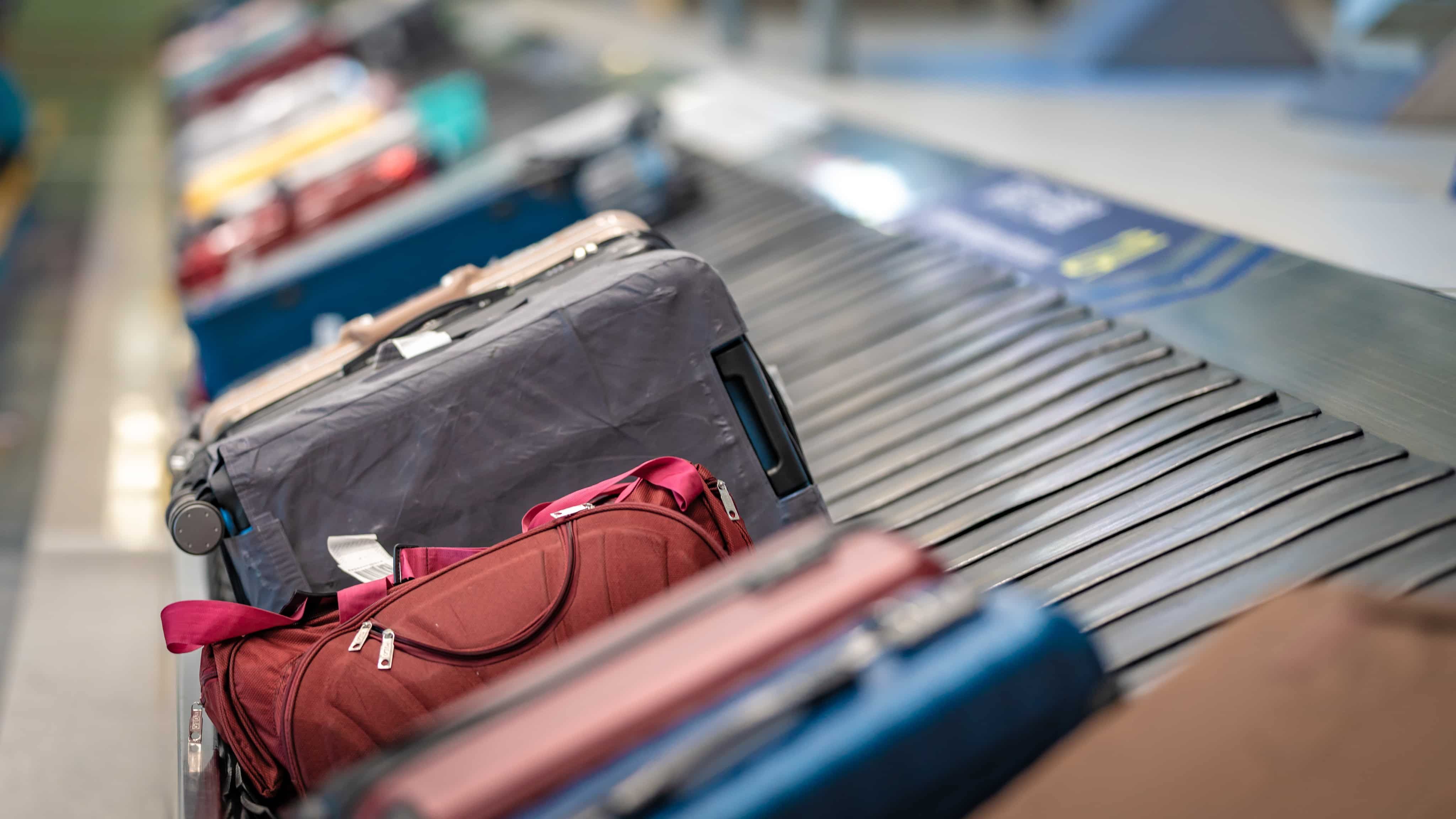 Assorted suitcases and a red duffel on an airport baggage carousel