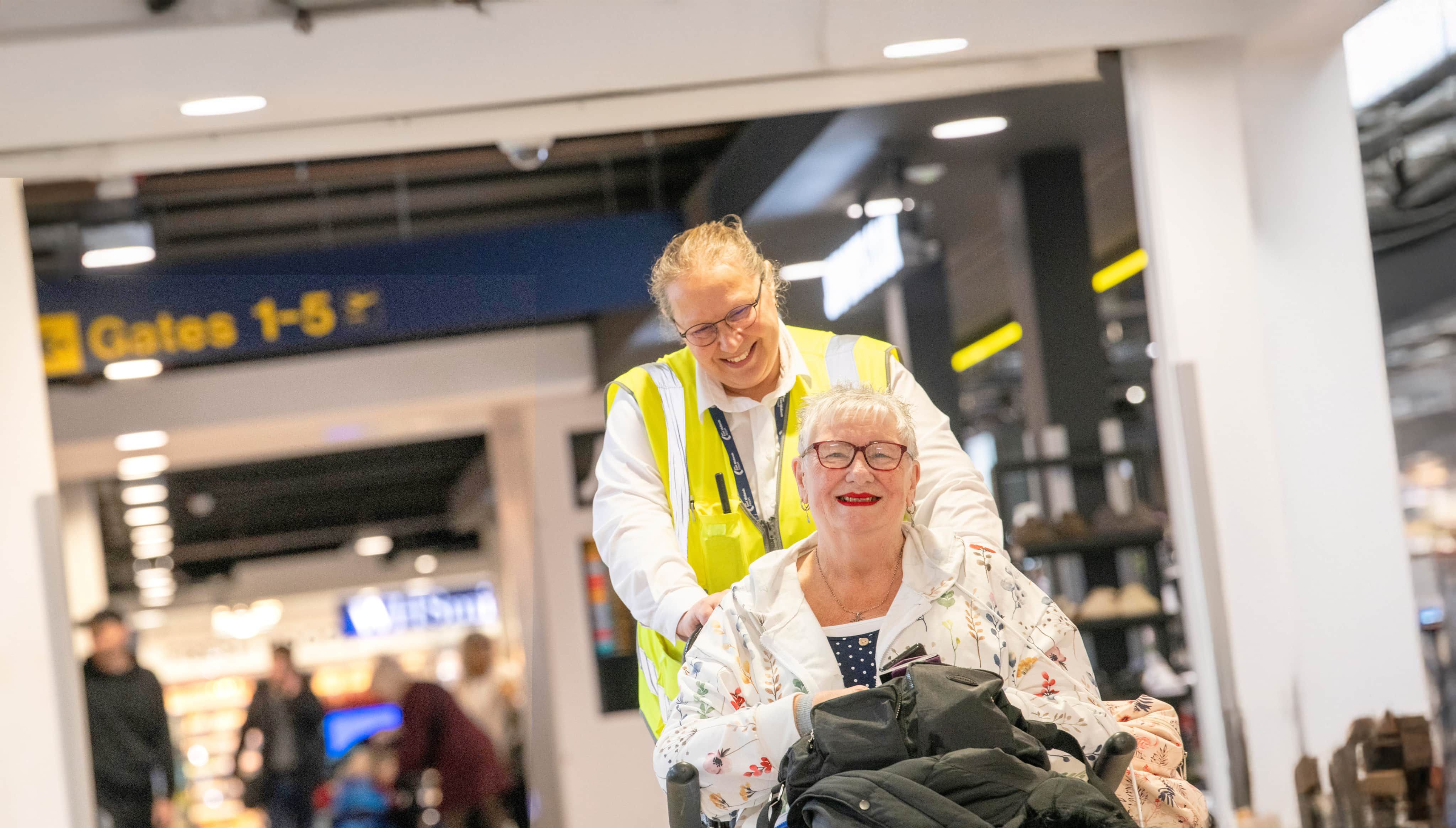 Assisted Travel team member pushing passenger in wheelchair through airport