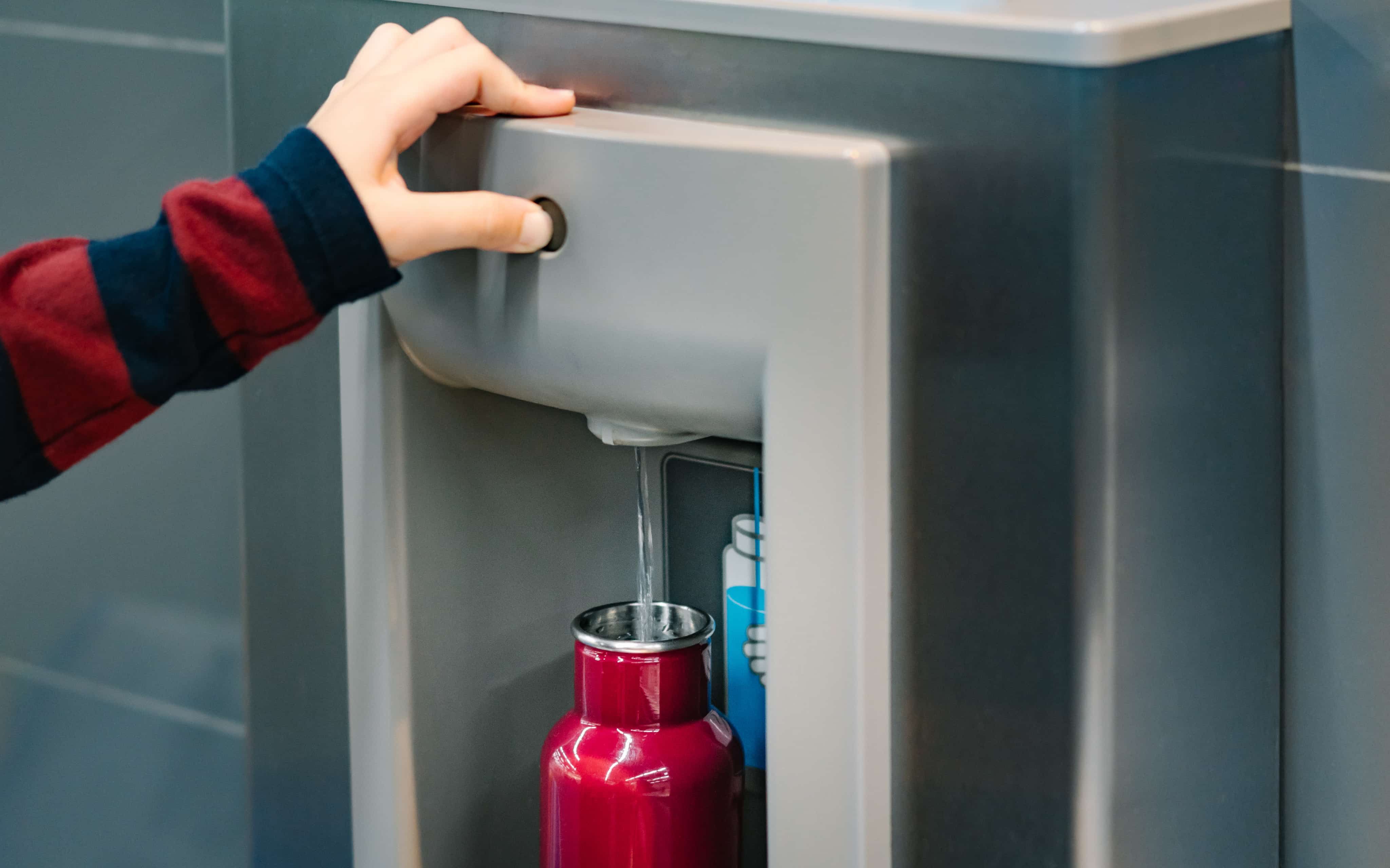 Person holding button down to fill up water bottle
