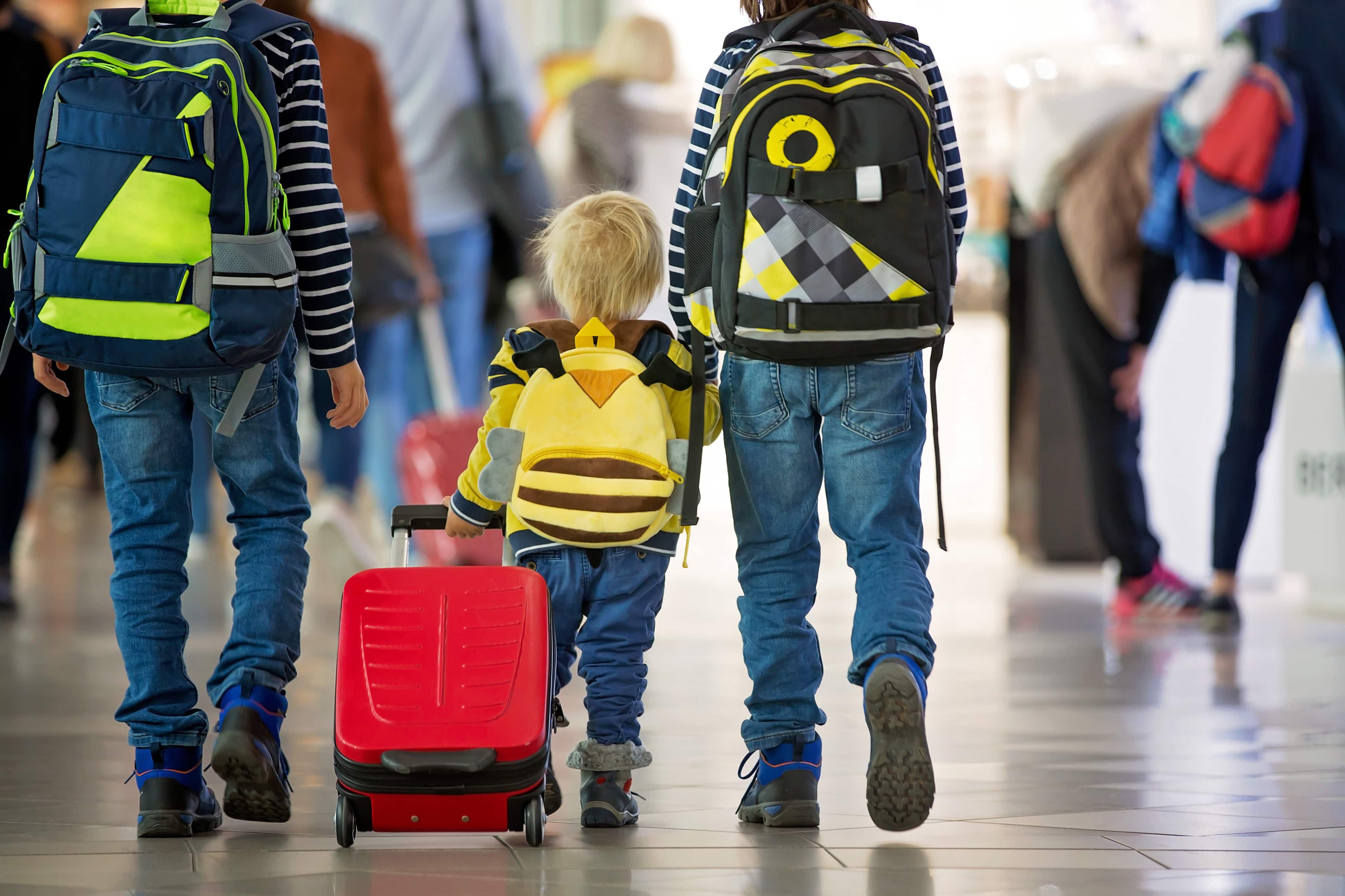 Couple holding hands with child pulling suitcase