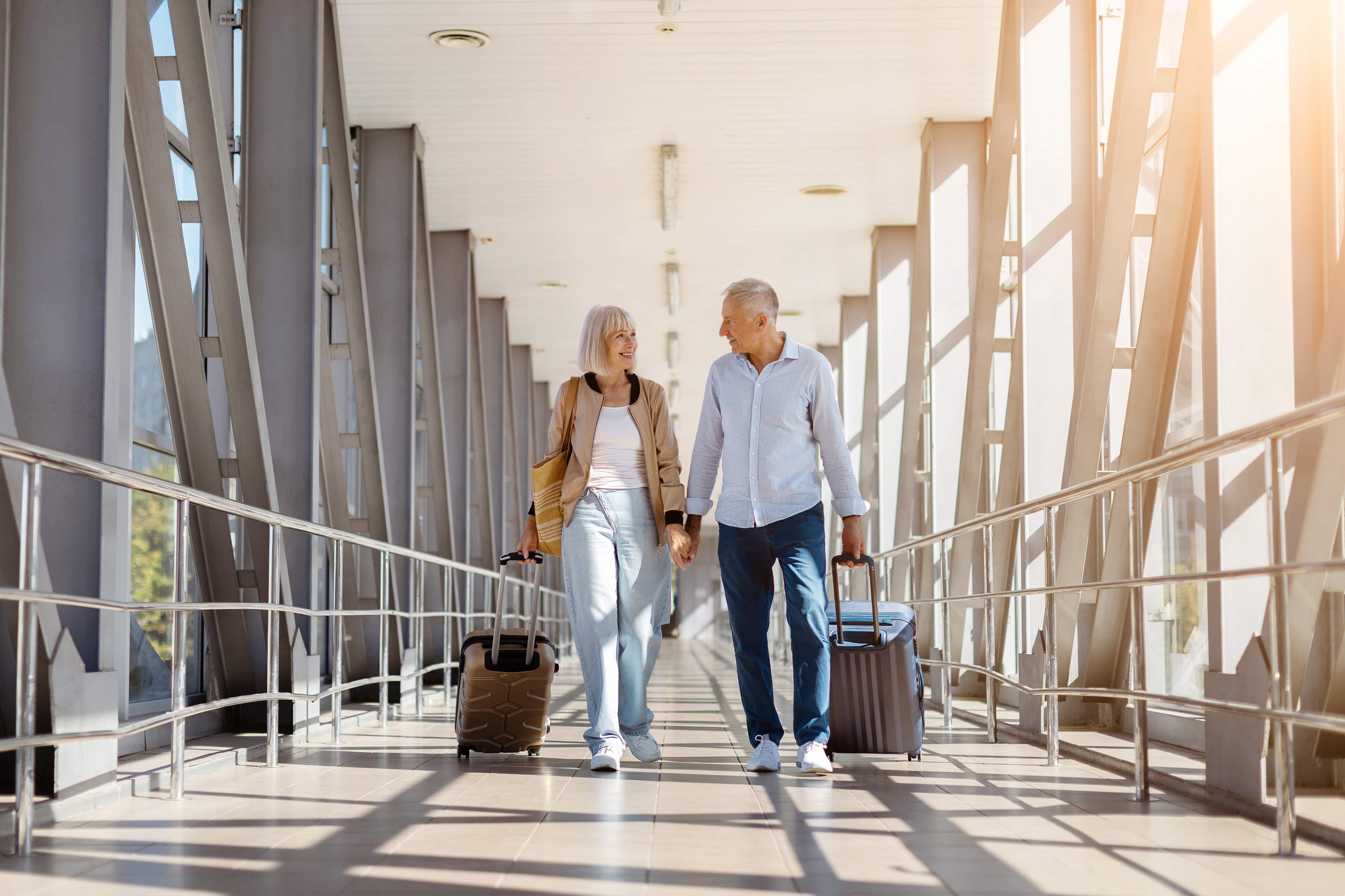 Couple holding hands walking with suitcases