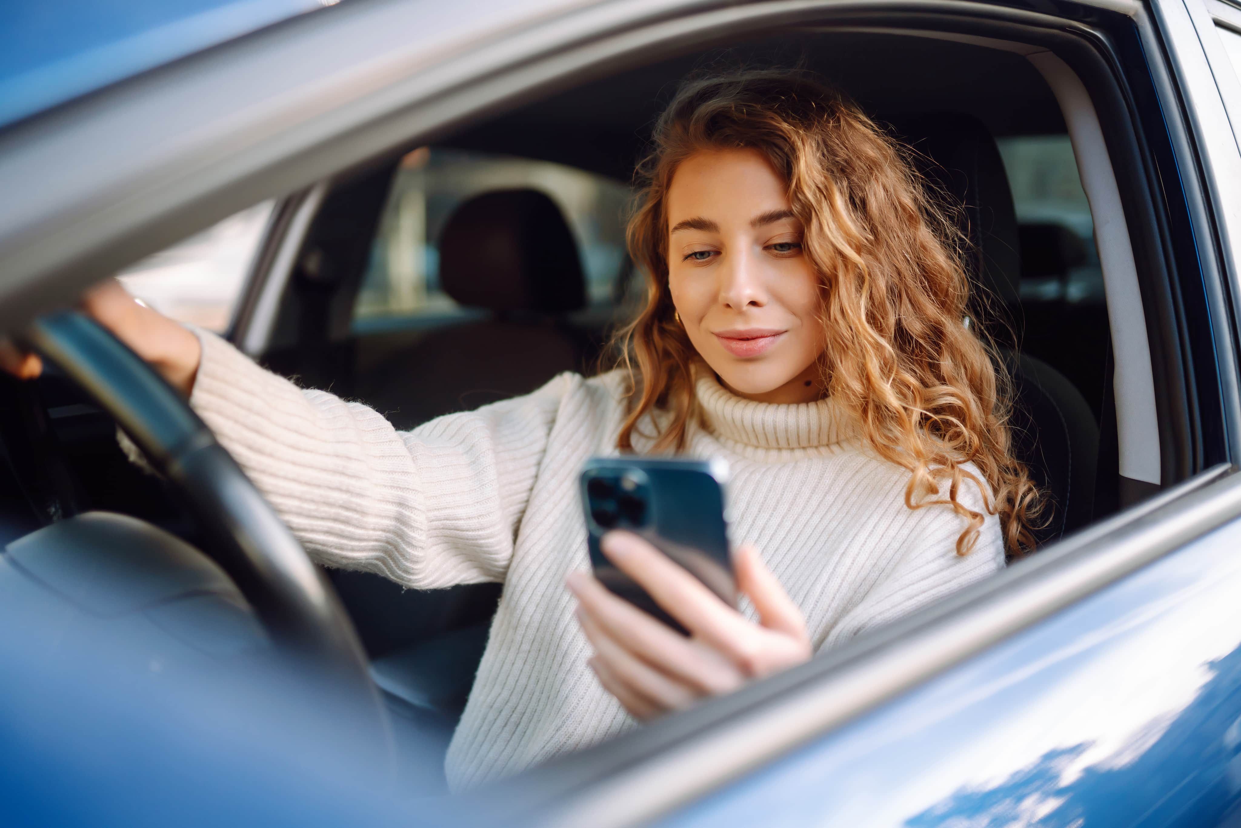 Woman looking at phone in car