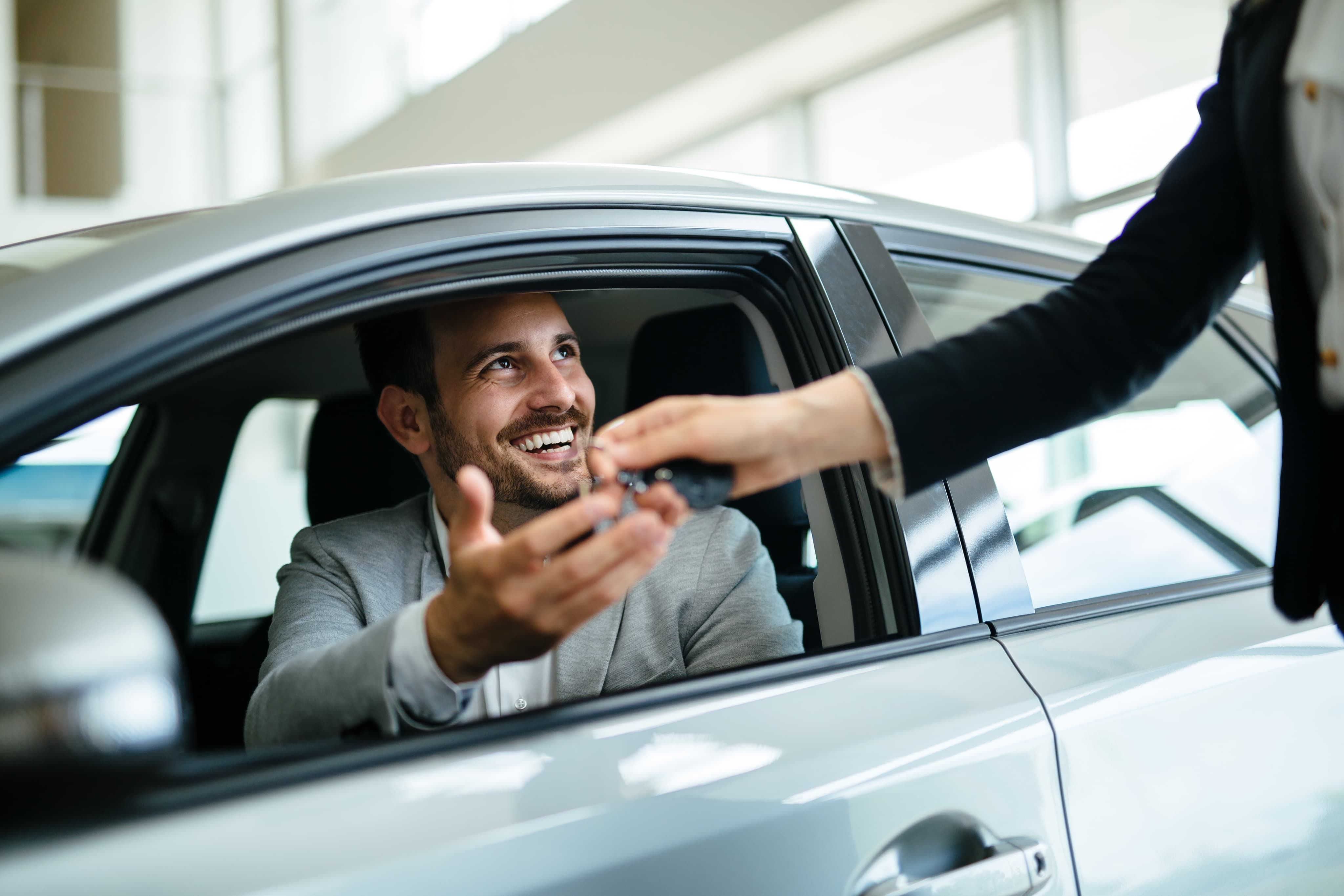 Handing over keys to smiling man in car
