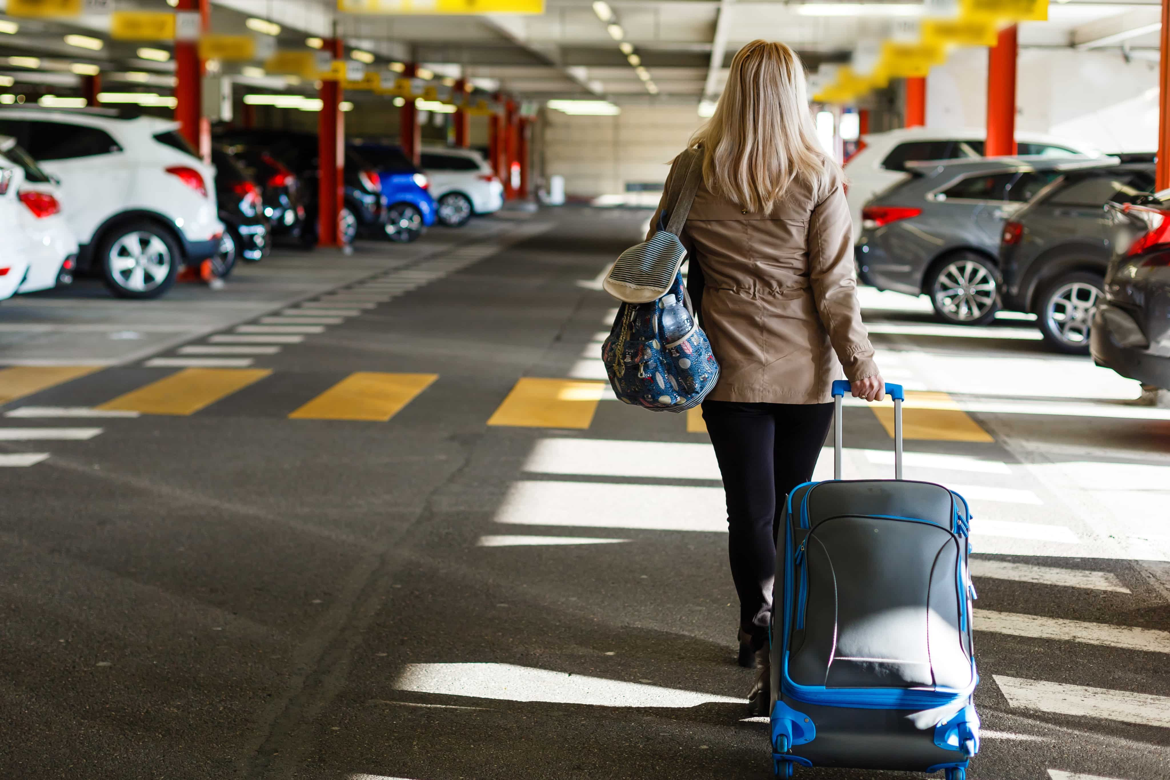 Woman walking through car park with suitcase