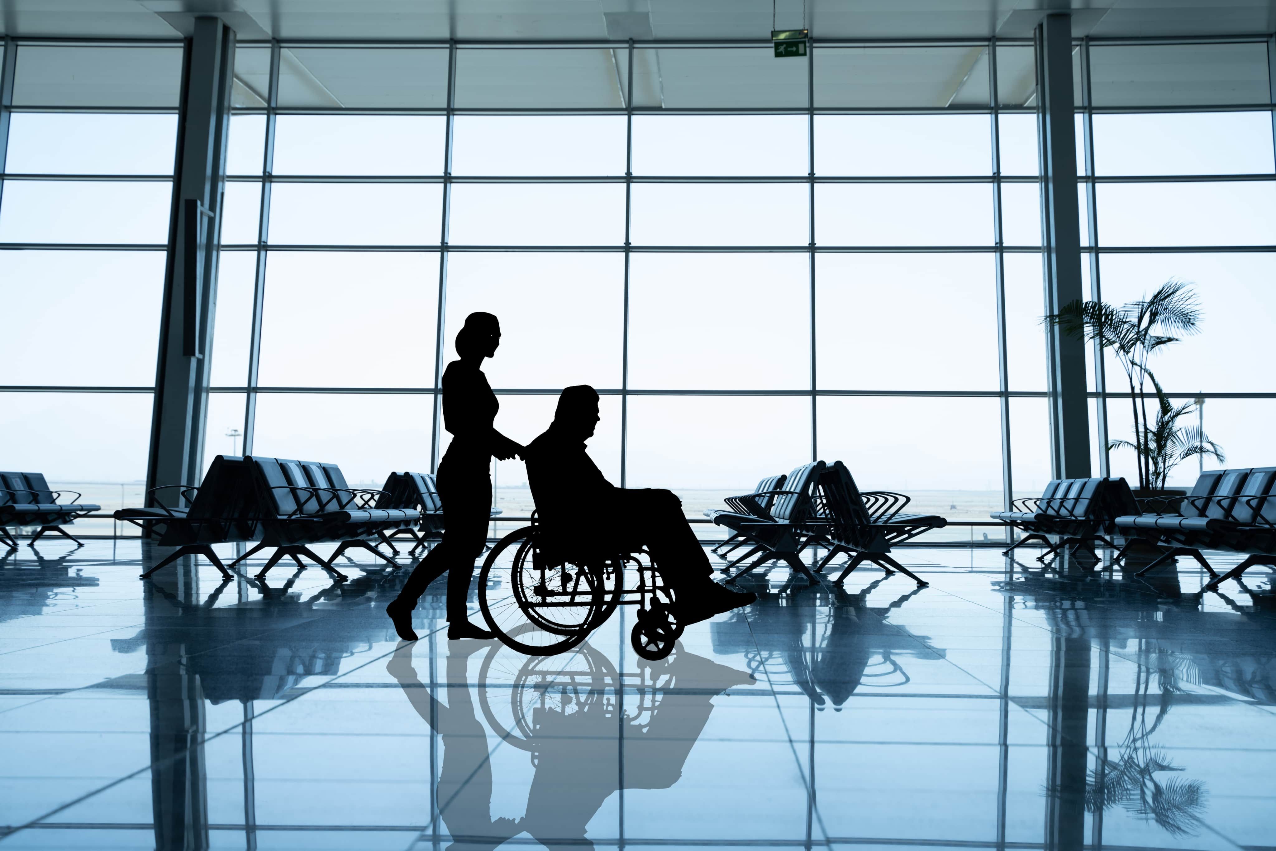 Woman pushing man through airport on wheelchair