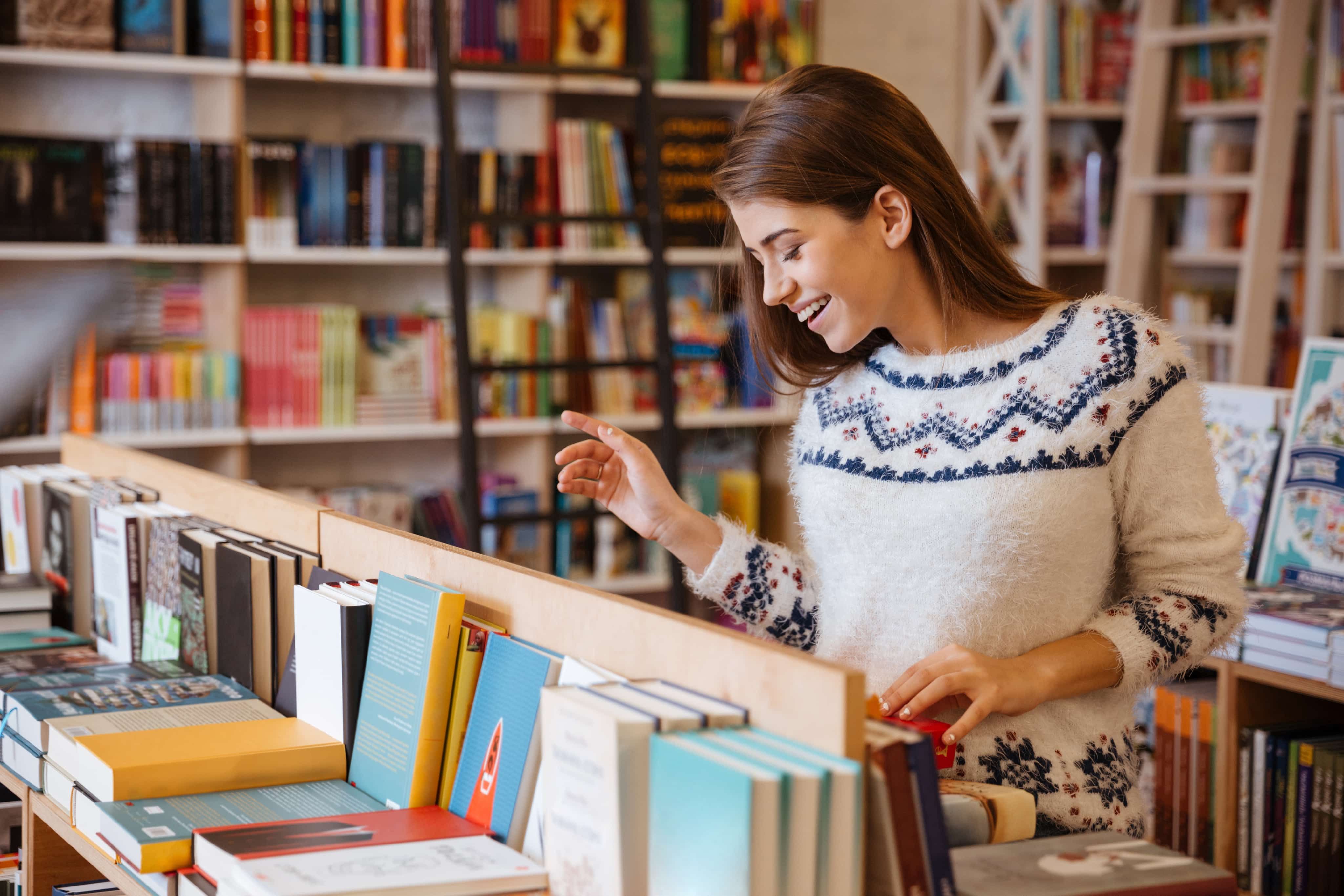 Woman laughing looking at books on shelf in shop