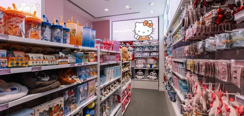 Toy store aisle with colourful stuffed animals, drink bottles, and accessories, featuring a prominent Hello Kitty display on the back wall.