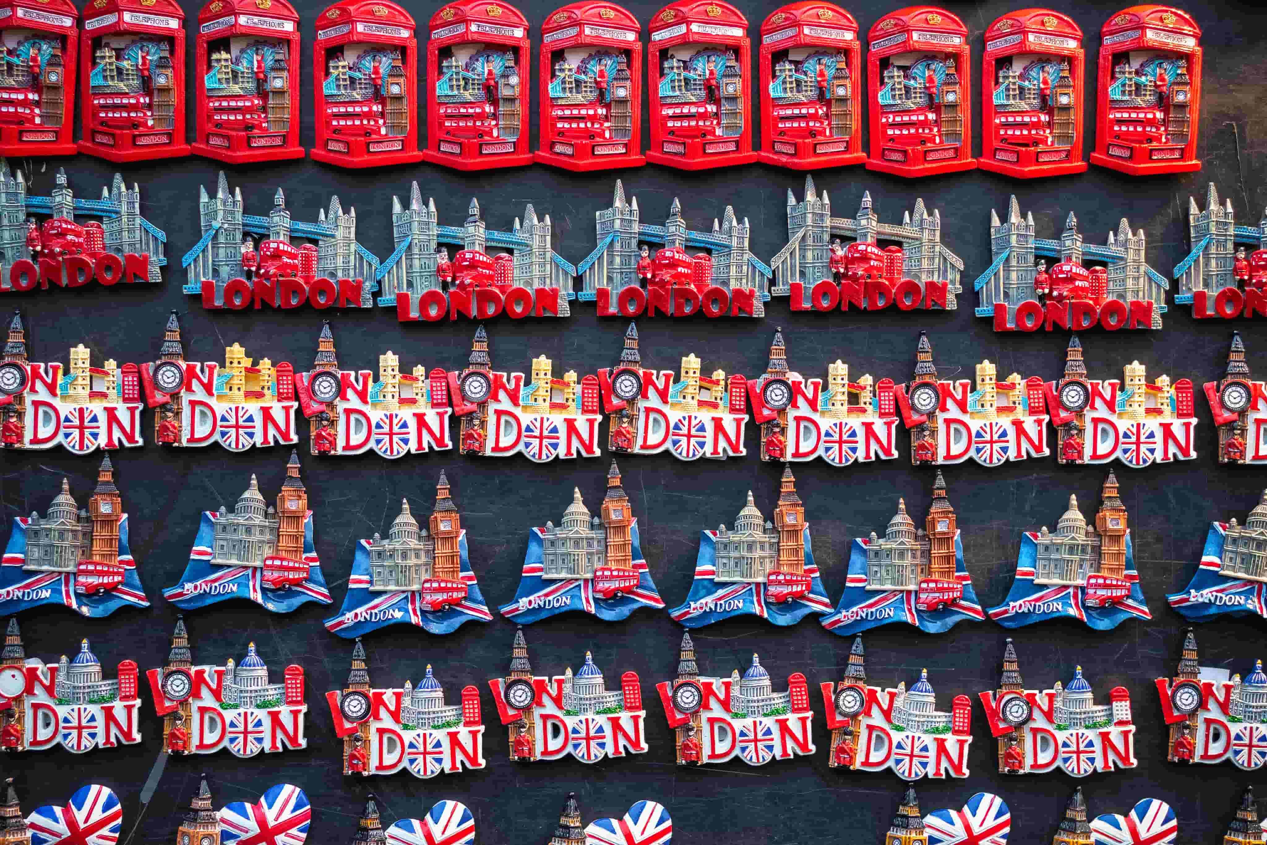 Rows of colorful London souvenir magnets, featuring red phone booths, Tower Bridge, Big Ben, Union Jack motifs and "London" lettering.