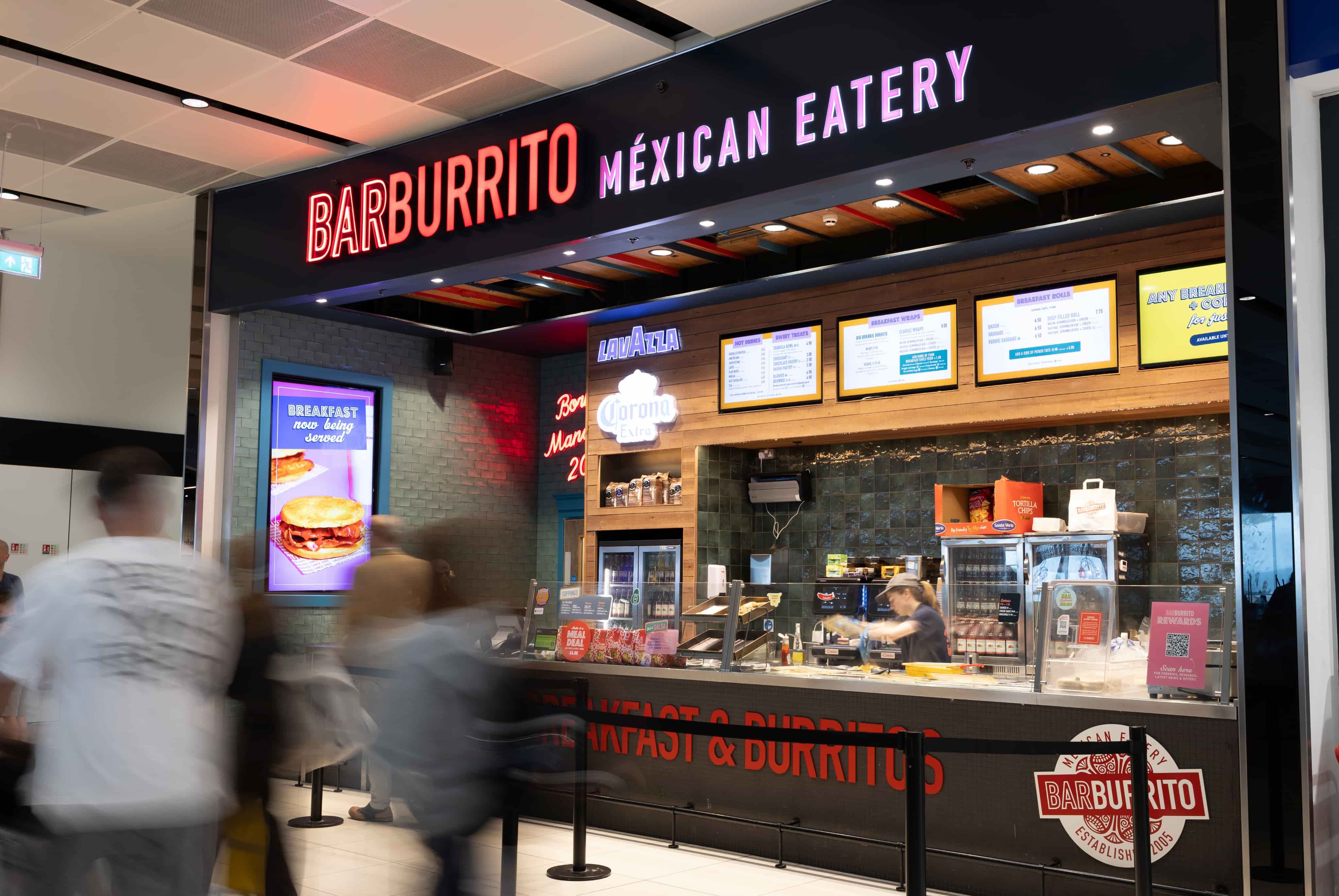 People ordering at a modern Mexican eatery named "Barburrito" with digital menu boards and a visible kitchen area.