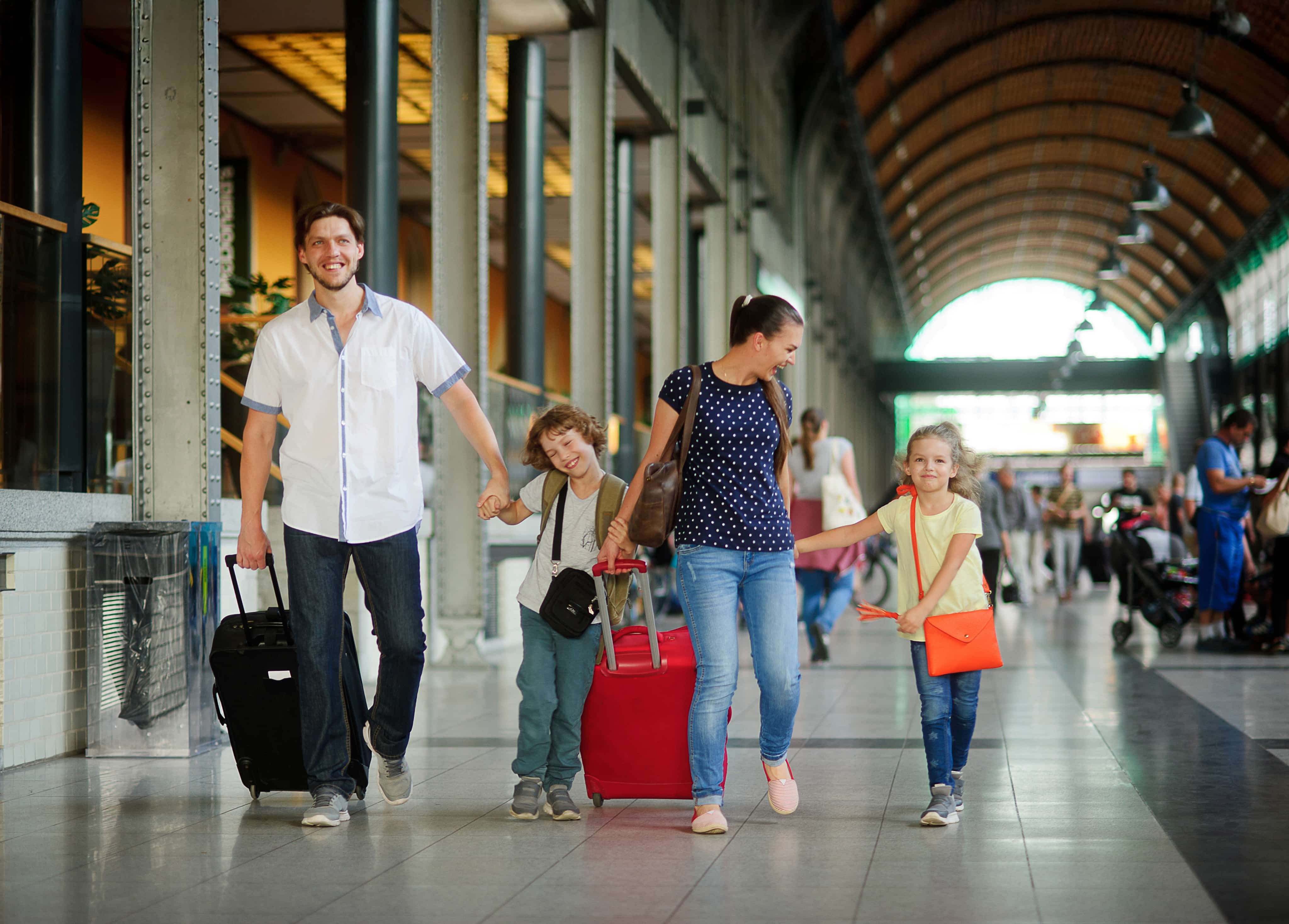 Family with little children walking along with suitcases