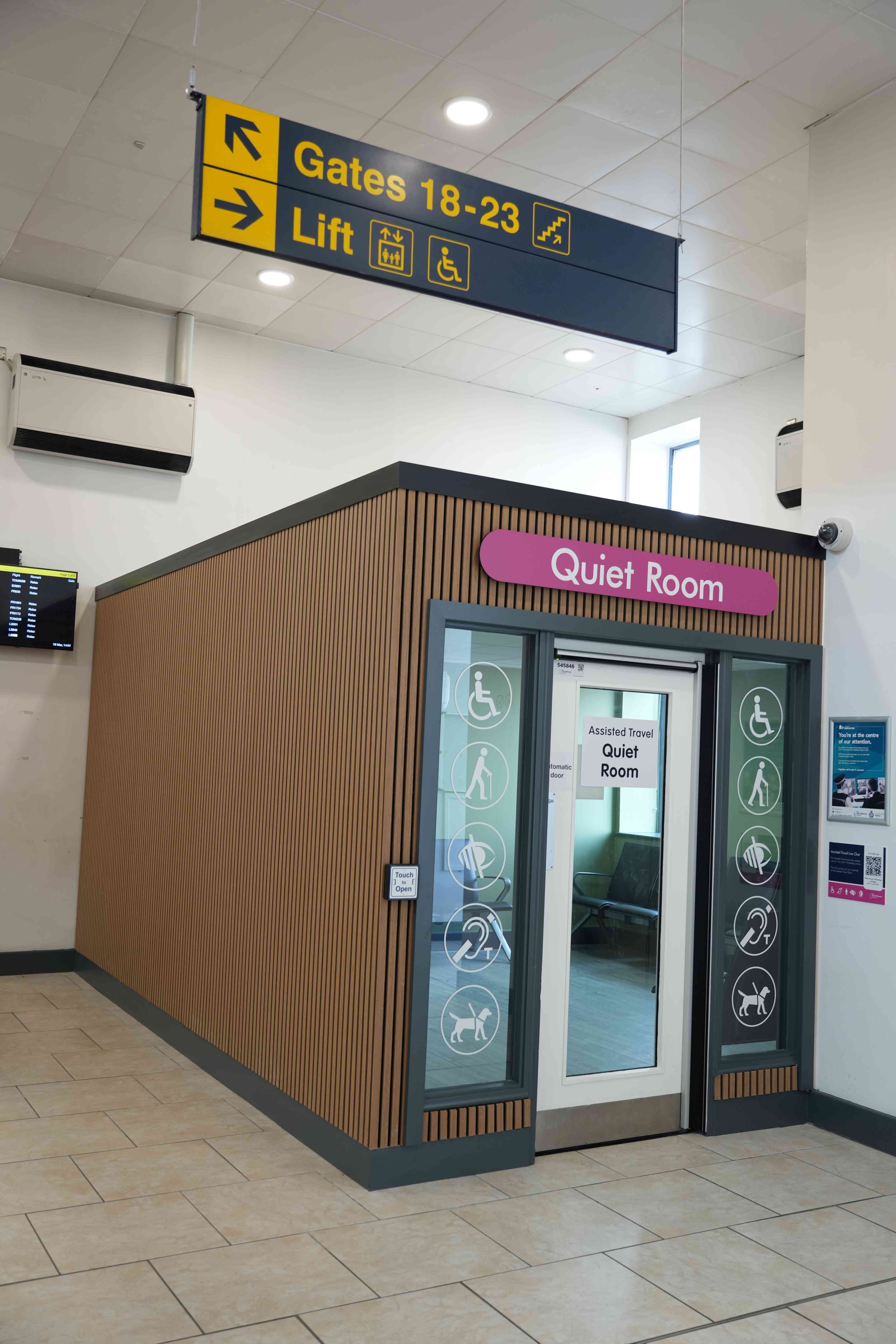 A quiet room at an airport, marked with accessibility symbols, located near Gates 18-23 and a lift.