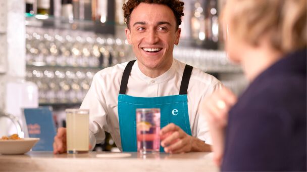 a barman serving a drink to a female customer