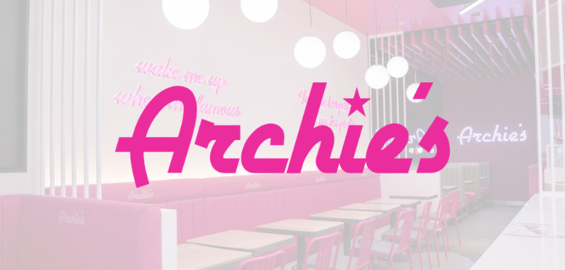 Interior of Archie's diner with pink seating and neon signs. Large pink "Archie's" logo overlays the image, featuring modern décor.