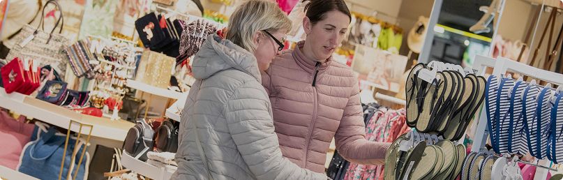 Two women looking at flip flops in shop