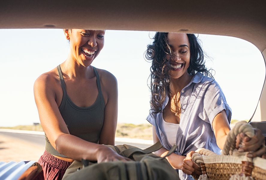 Two women getting bags out of car boot